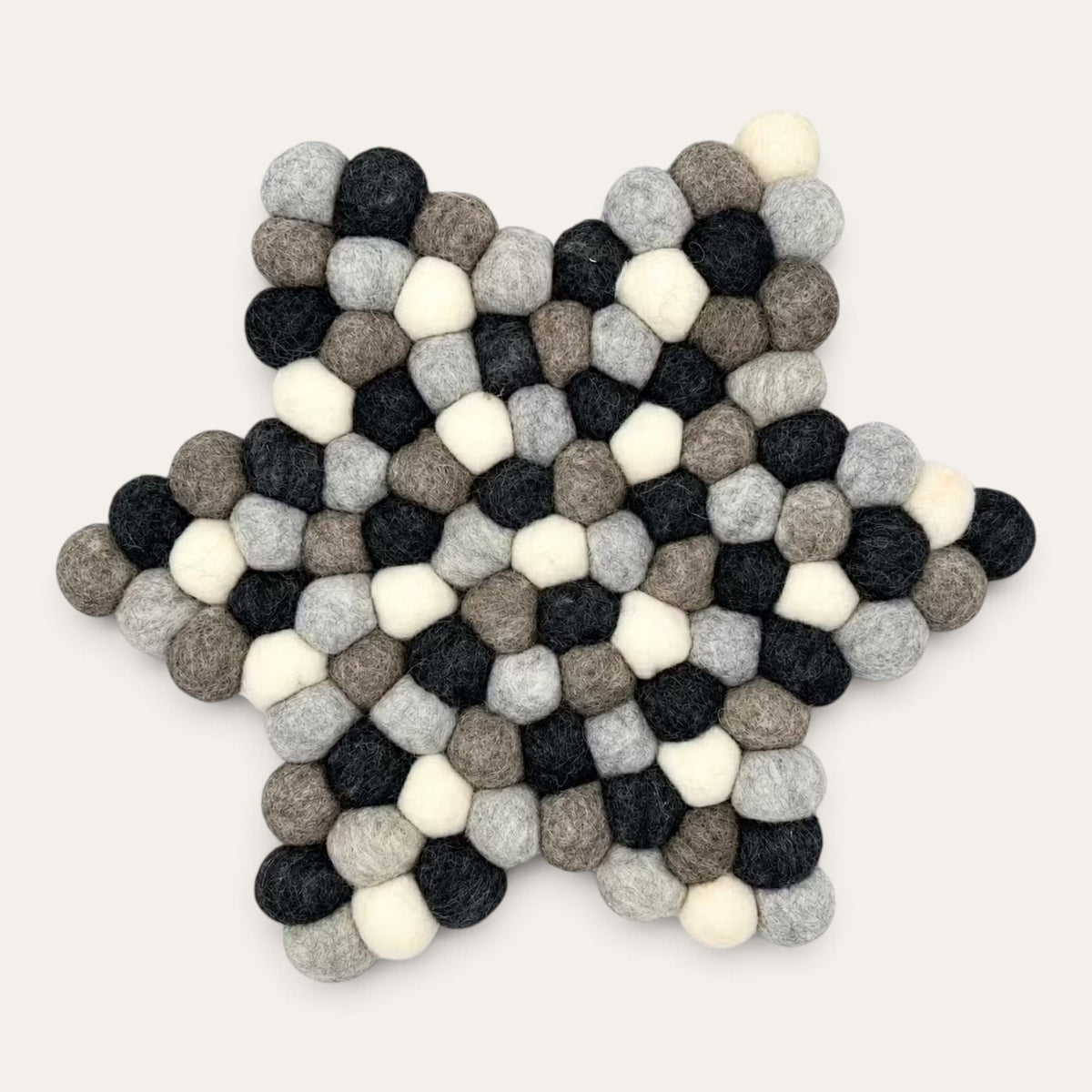 Grey felt ball star-shaped centre mat seen from above, in charcoal, grey, taupe and cream wool balls