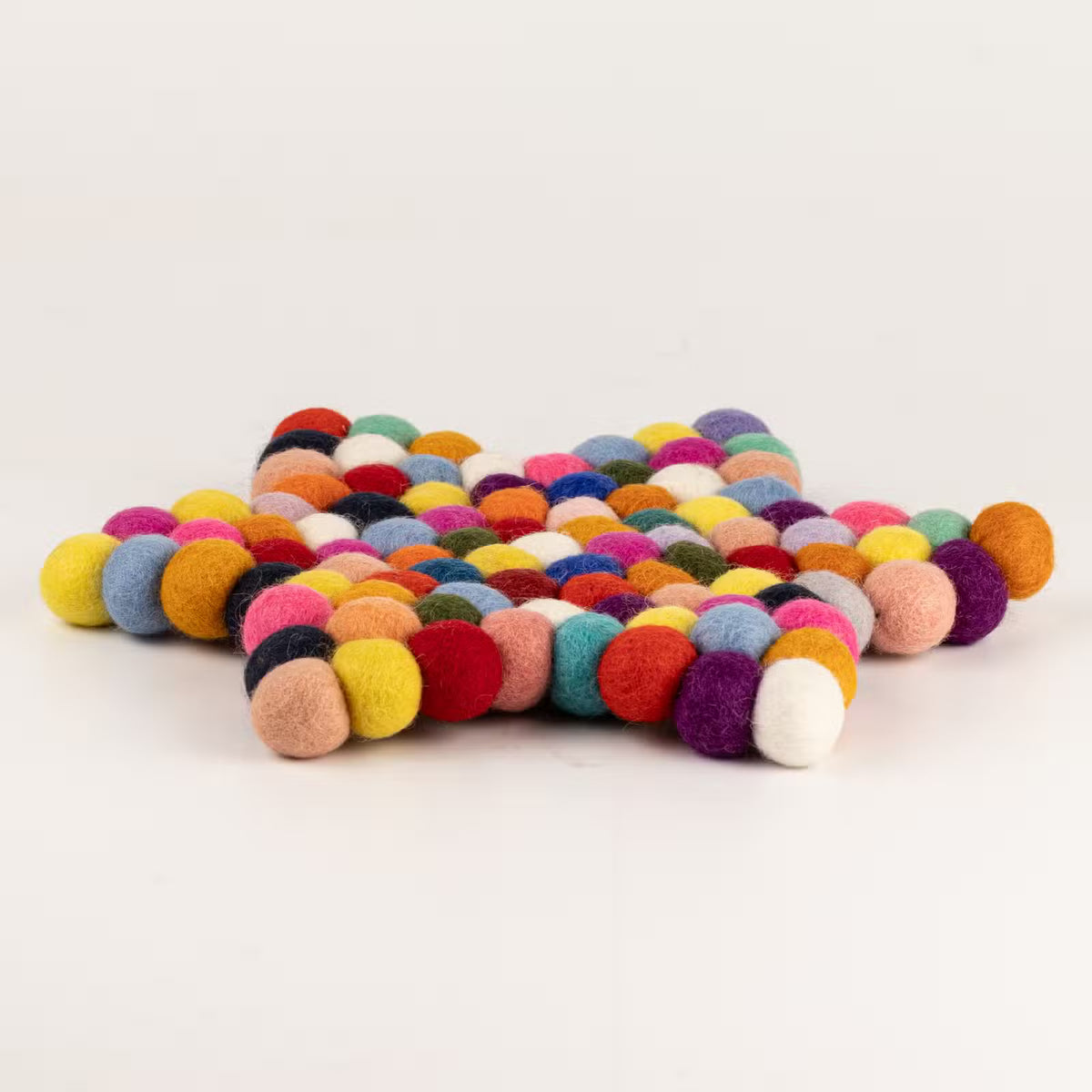 Side view of the multicolour felt ball star mat showing its thickness