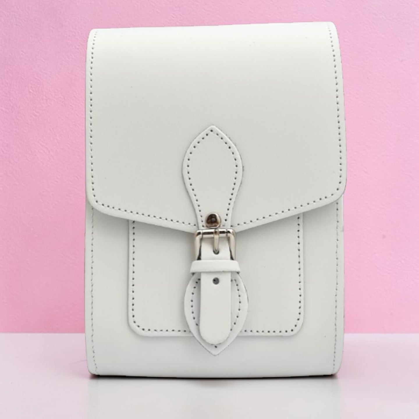 White leather wallet with a strap on a pink background
