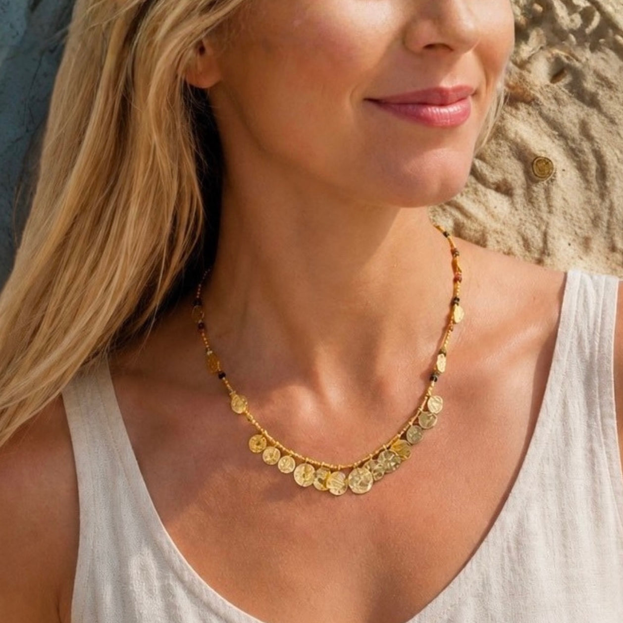 Woman wearing a gold necklace with a neutral background