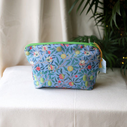 Garden Fruits everyday pouch with a bright green zip on a cream cloth in front of a palm plant