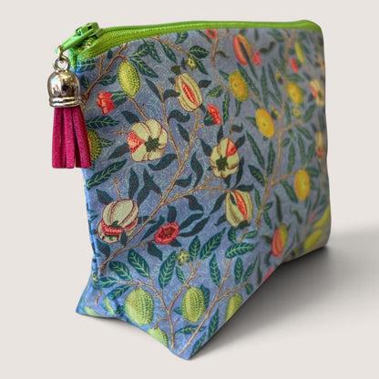 Garden Fruits everyday pouch in a William Morris fruit print on blue, with a green zip and magenta suede tassel, angled view
