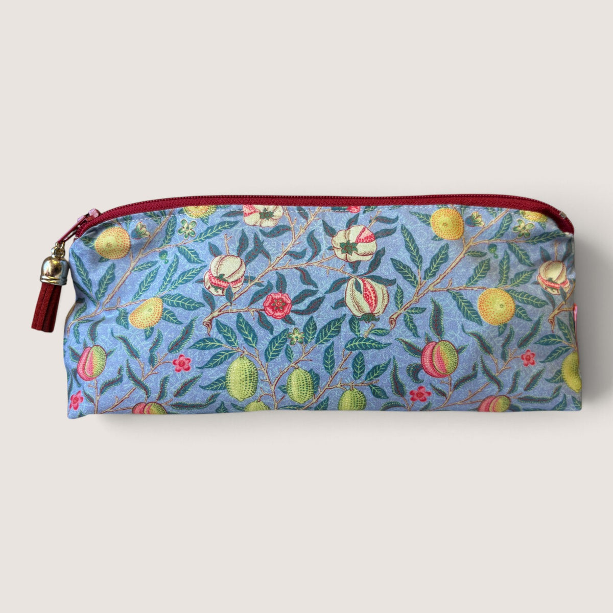 Front of the Garden Fruits pencil case in a William Morris fruit print with a red zip and tassel