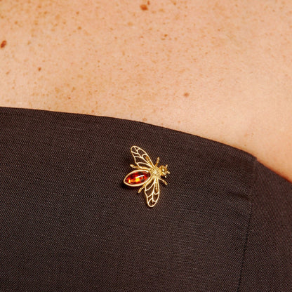 Gold insect brooch on a black fabric background