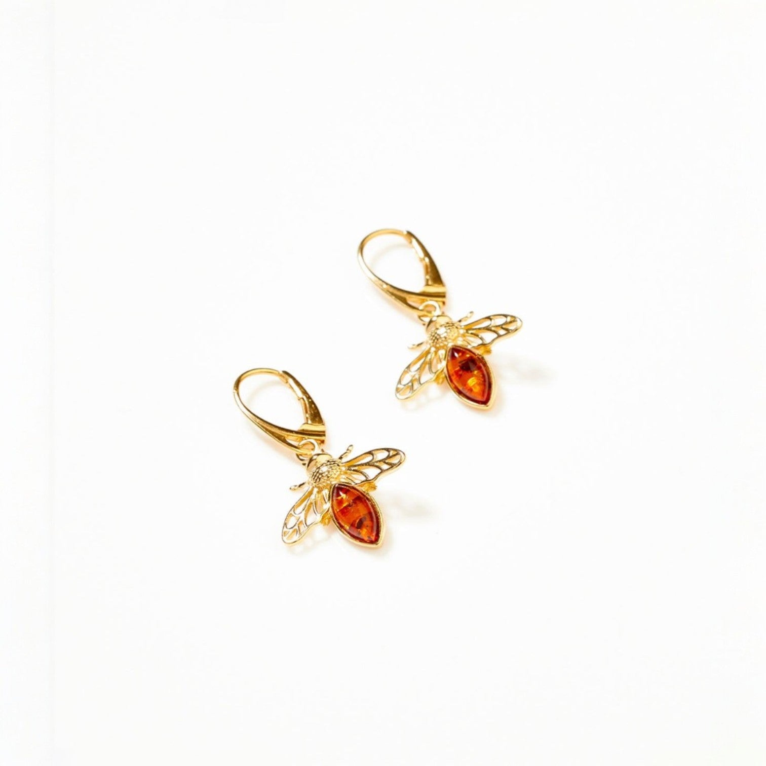 Gold bee-shaped earrings with red gemstones on a white background