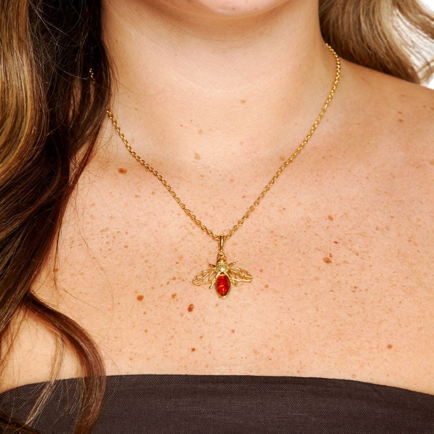 Gold necklace with a red pendant on a person's neck