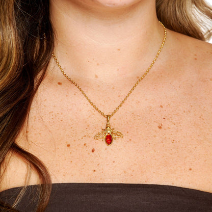 Gold necklace with a red pendant on a person's neck