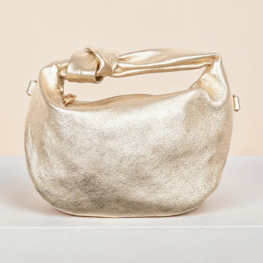Gold metallic handbag on a light background