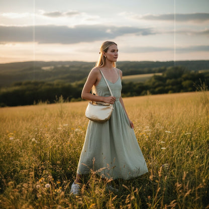 Woman in a light dress standing in a field with a sunset in the background
