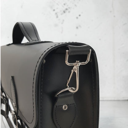 Black leather handbag with a silver clasp on a light gray background