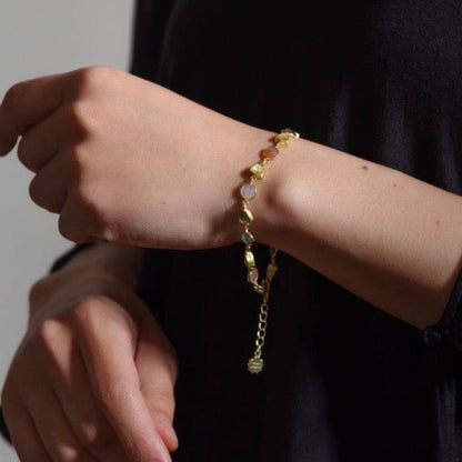 Person wearing a gold bracelet on a plain background
