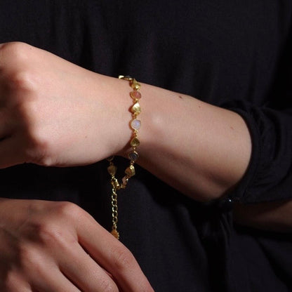 Gold bracelet on a wrist with a dark background