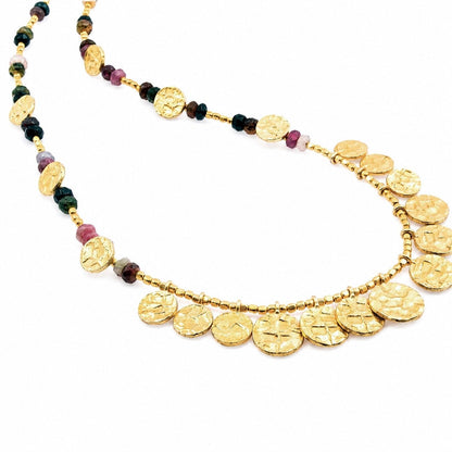 Gold necklace with coin-shaped beads on a white background