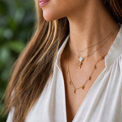 Close-up of a woman wearing gold necklaces with a blurred green background