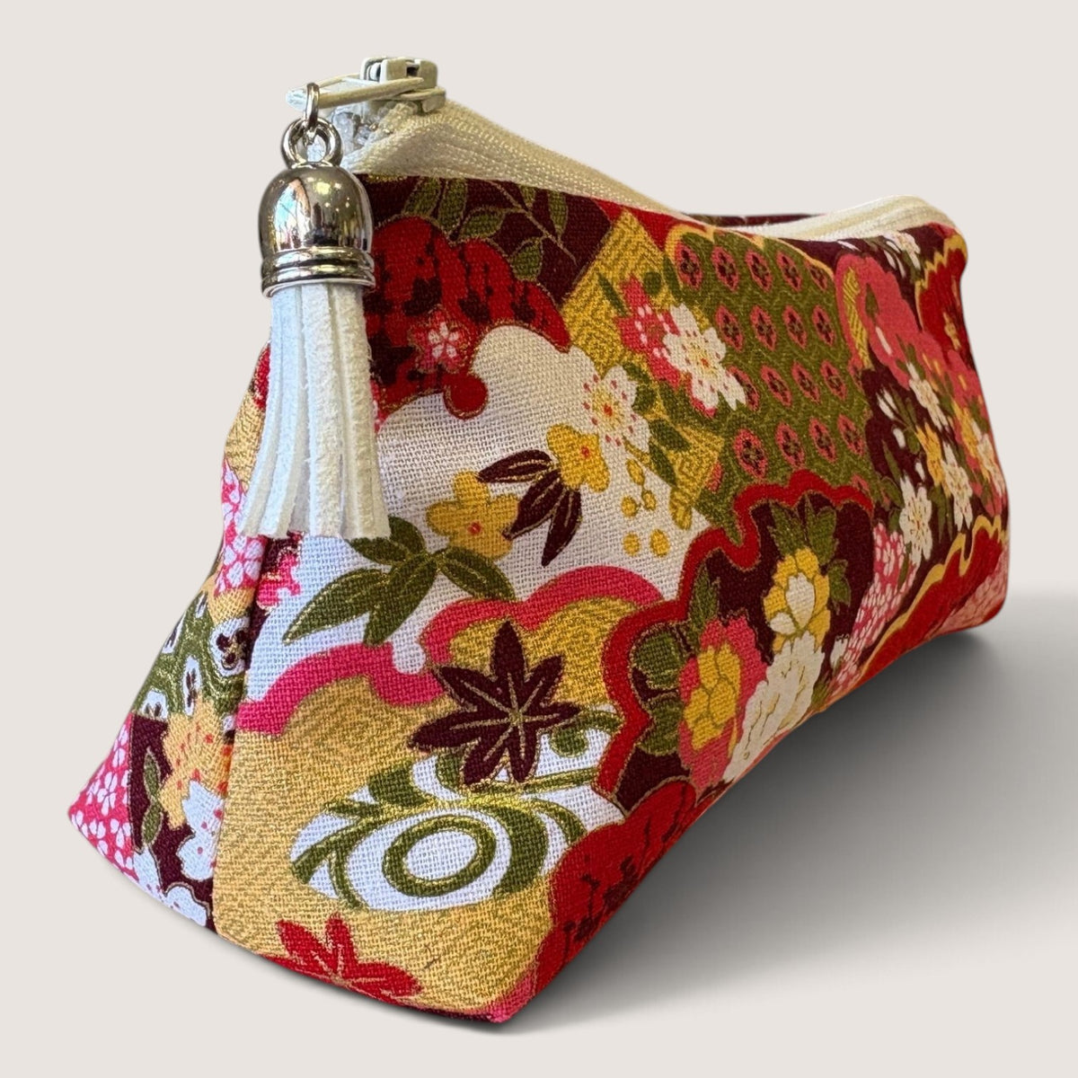 Isumi Red Japanese pencil case with a cream zip and white suede tassel, angled view
