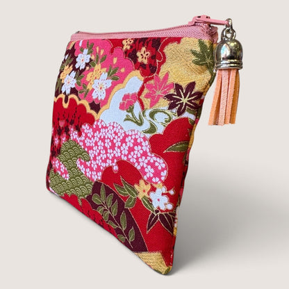 Isumi Red Japanese purse with a pink zip and peach suede tassel, angled view