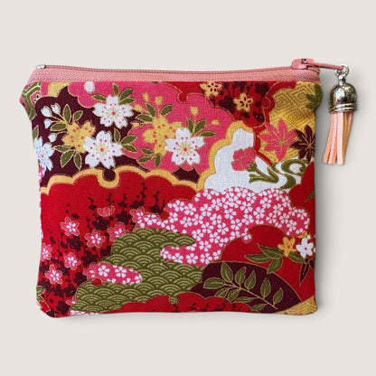 Front of the Isumi Red Japanese purse in a red and pink cherry blossom print with a pink zip and peach tassel