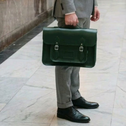 Person holding a green leather briefcase on a tiled floor.