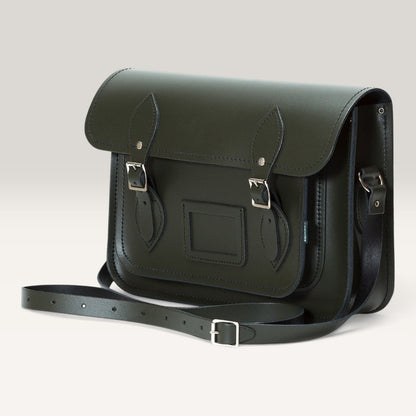 A dark olive green leather satchel bag with silver-tone buckles and a matching shoulder strap, photographed on a clean light gray background.
