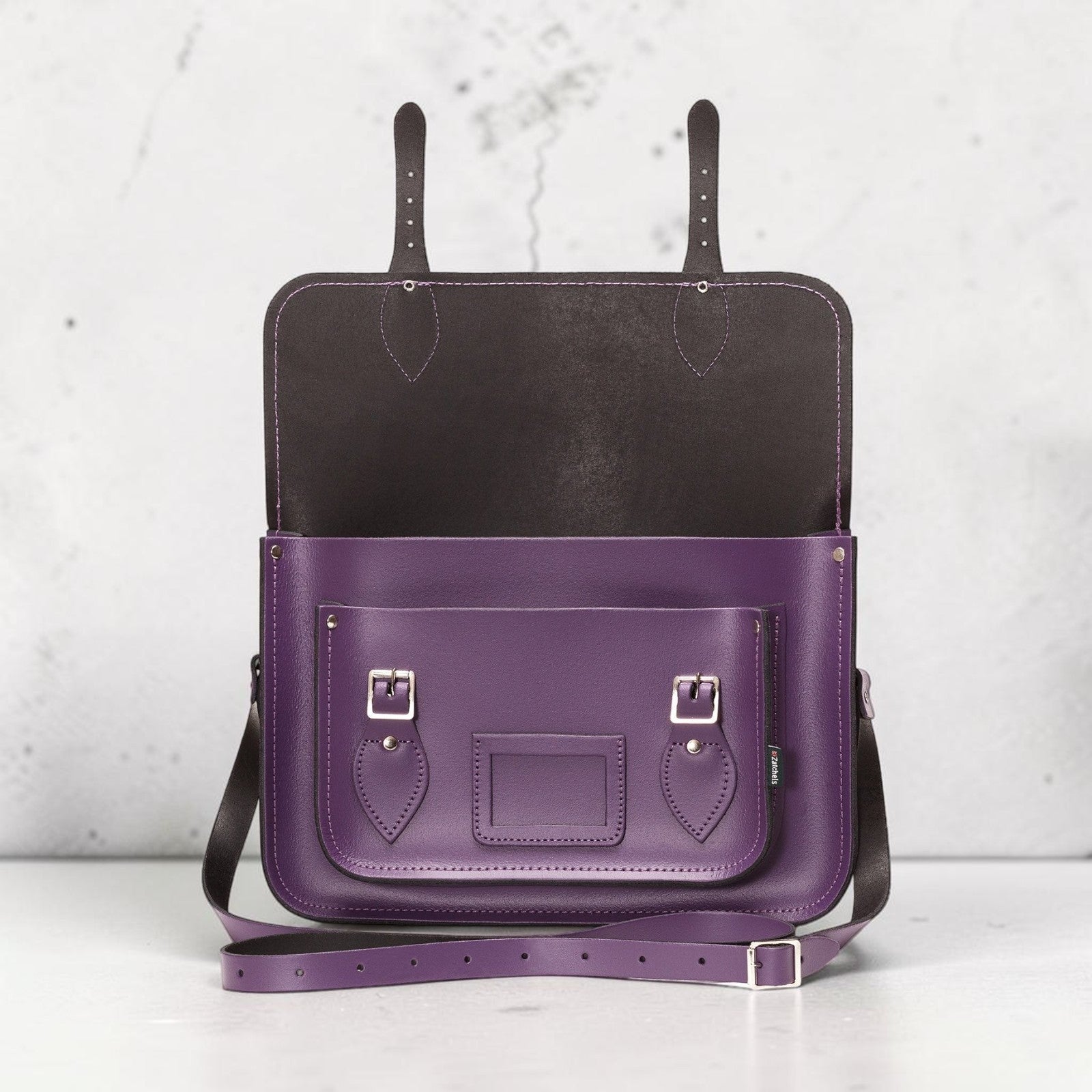 Purple leather bag with black interior on a light gray background