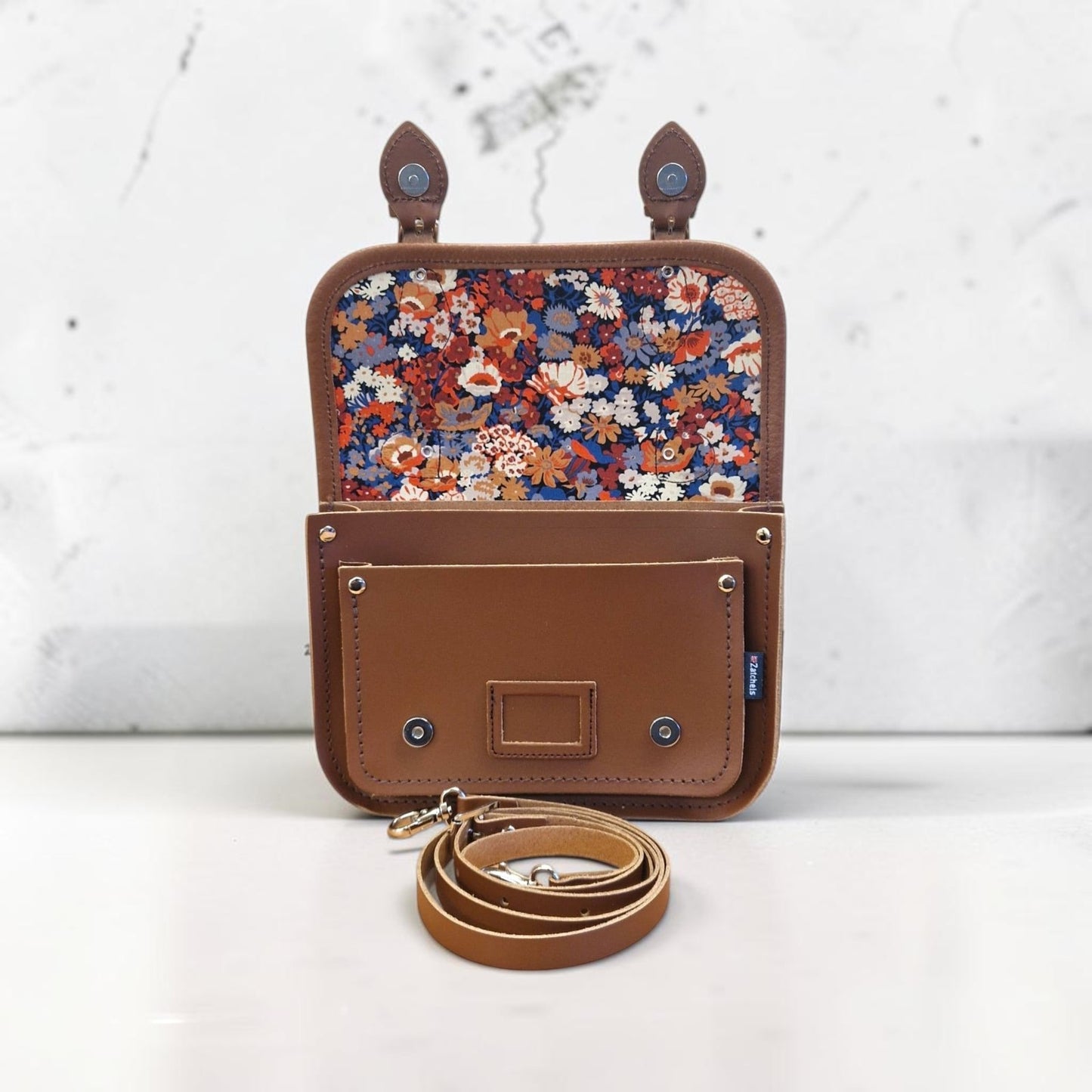 Brown leather pouch with floral interior on a white background