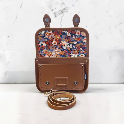 Brown leather pouch with floral interior on a white background