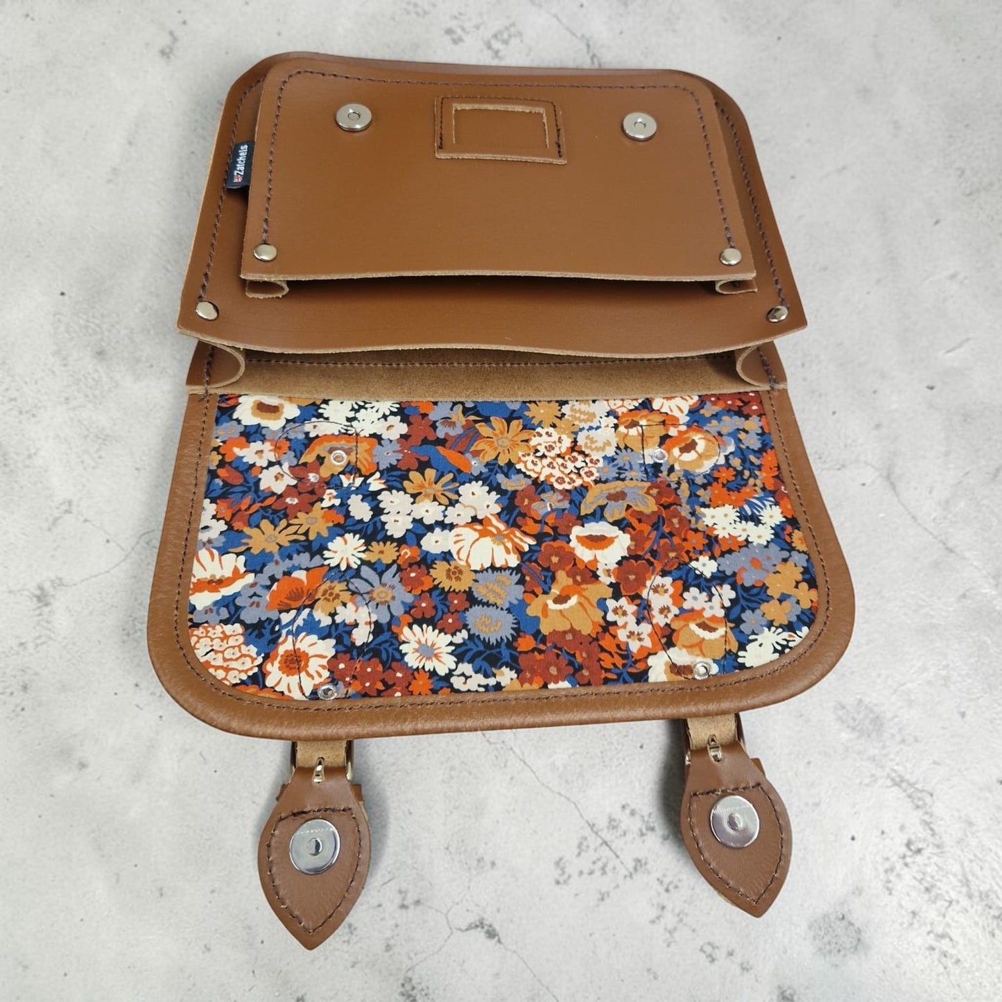 Brown leather bag with floral pattern on a light gray background