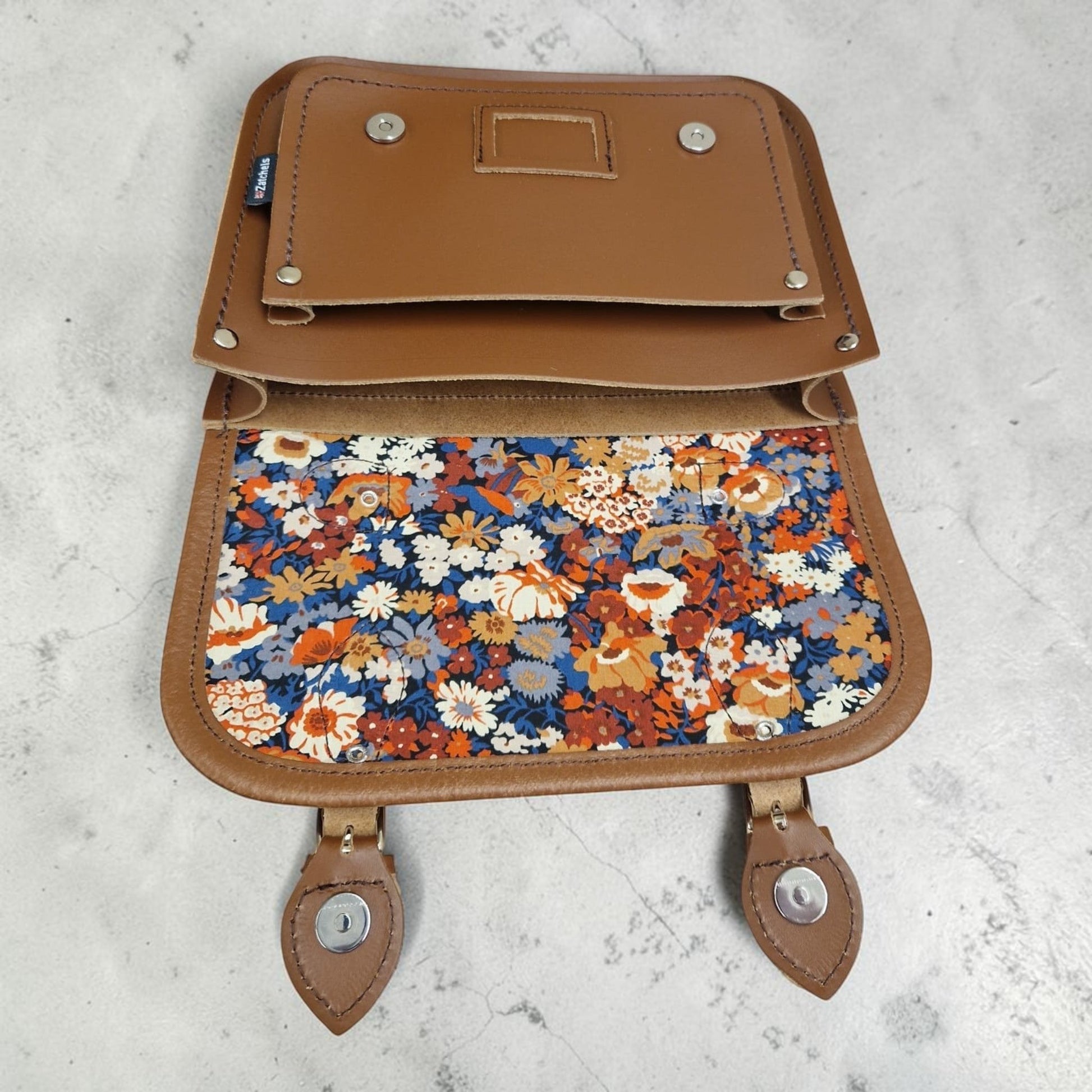Brown leather bag with floral pattern on a light gray background