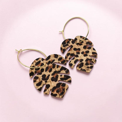 Leopard print leaf-shaped earrings on a pink background