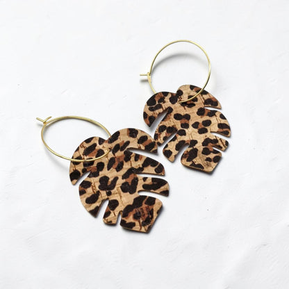 Leopard print leaf-shaped earrings on gold hoops against a white background