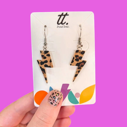 Leopard print lightning bolt earrings on a 'tt.' branded card against a purple background
