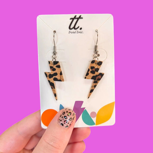 Leopard print lightning bolt earrings on a 'tt.' branded card against a purple background
