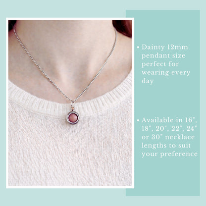Necklace with a pink pendant worn by a person, displayed against a light blue background.