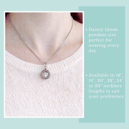Necklace with a pendant on a person wearing a white sweater, against a light blue background.