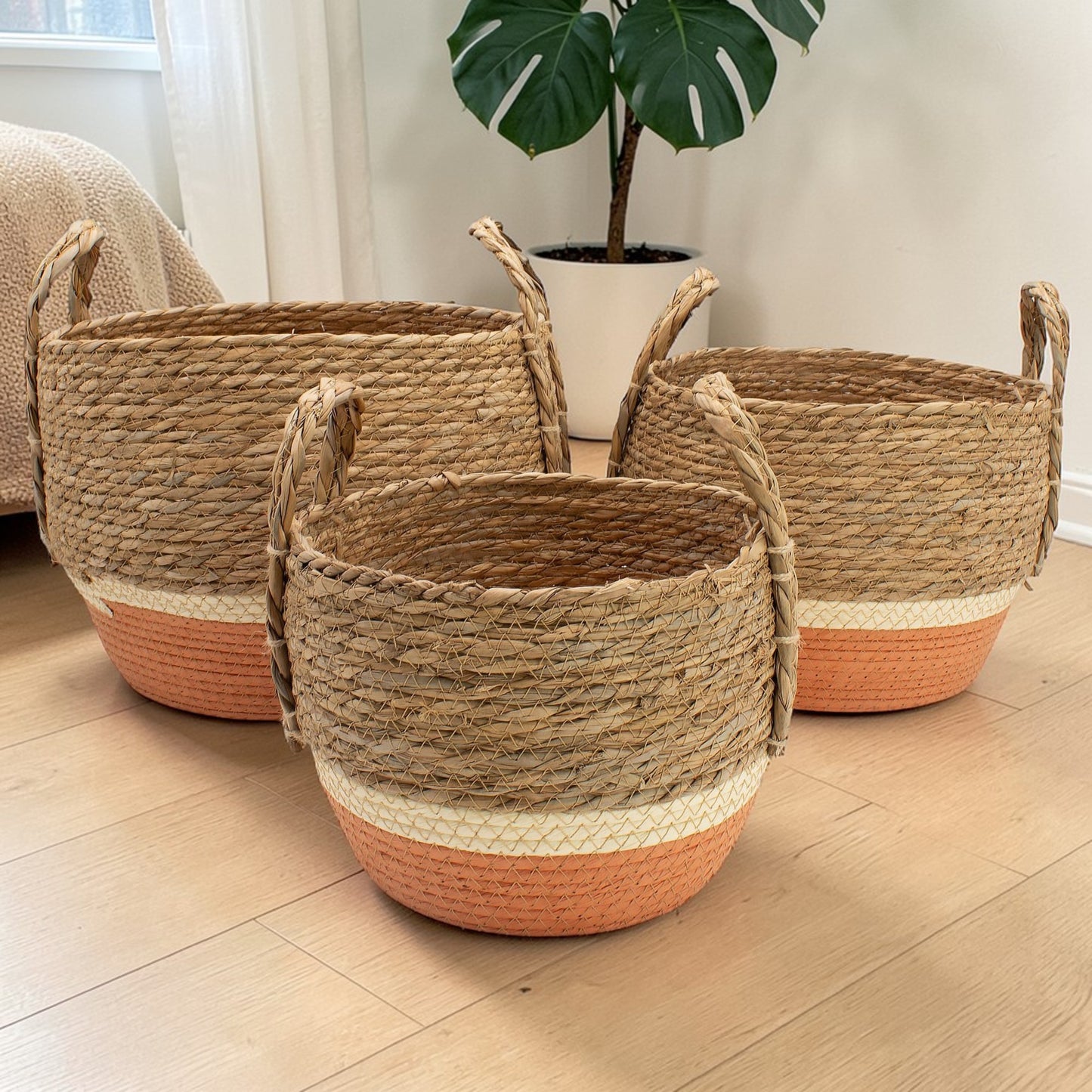 Three woven baskets with terracotta bases on a wooden floor.