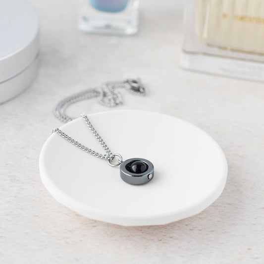 Necklace with a black pendant on a white dish, with a blurred background