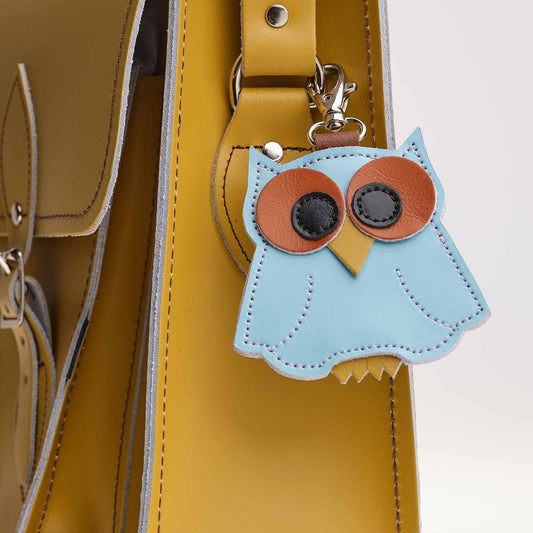Blue owl-shaped keychain attached to a yellow bag