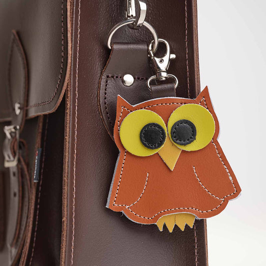 Owl-shaped keychain attached to a brown leather bag