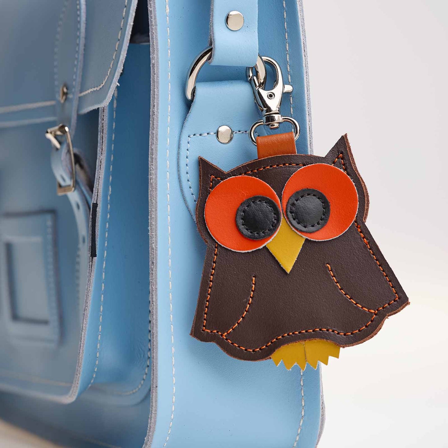 Leather owl keychain attached to a blue bag