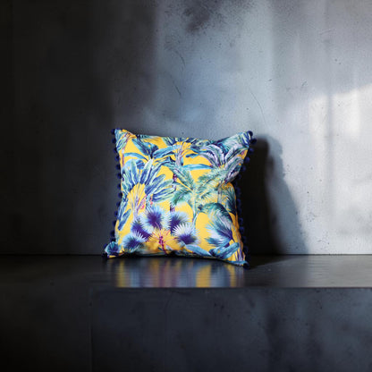 Palm Springs velvet cushion with navy pompoms, front view on a dark grey stand against a grey wall