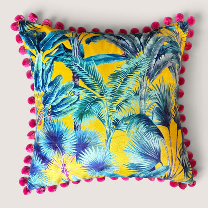 Palm Springs velvet cushion with strawberry pompoms, front view studio shot showing the yellow tropical palm print in teal, blue and purple, handmade in Dorset by Apricot Moon