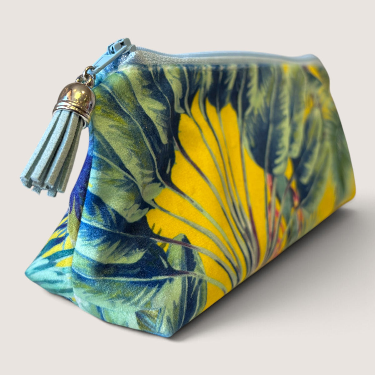 Palm Springs velvet pencil case angled to show the yellow and blue palm print, pale blue zip and blue suede tassel with a silver cap