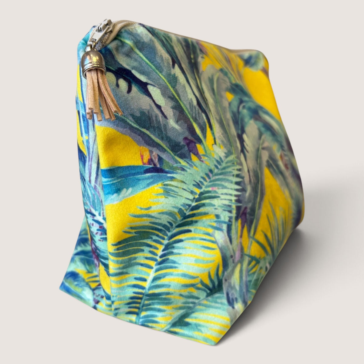 Palm Springs velvet wash bag angled to show the palm print, pale zip and tan suede tassel with a silver cap