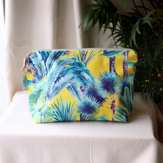 Palm Springs velvet wash bag with a pale grey zip and tan suede tassel on a cream cloth beside a palm plant
