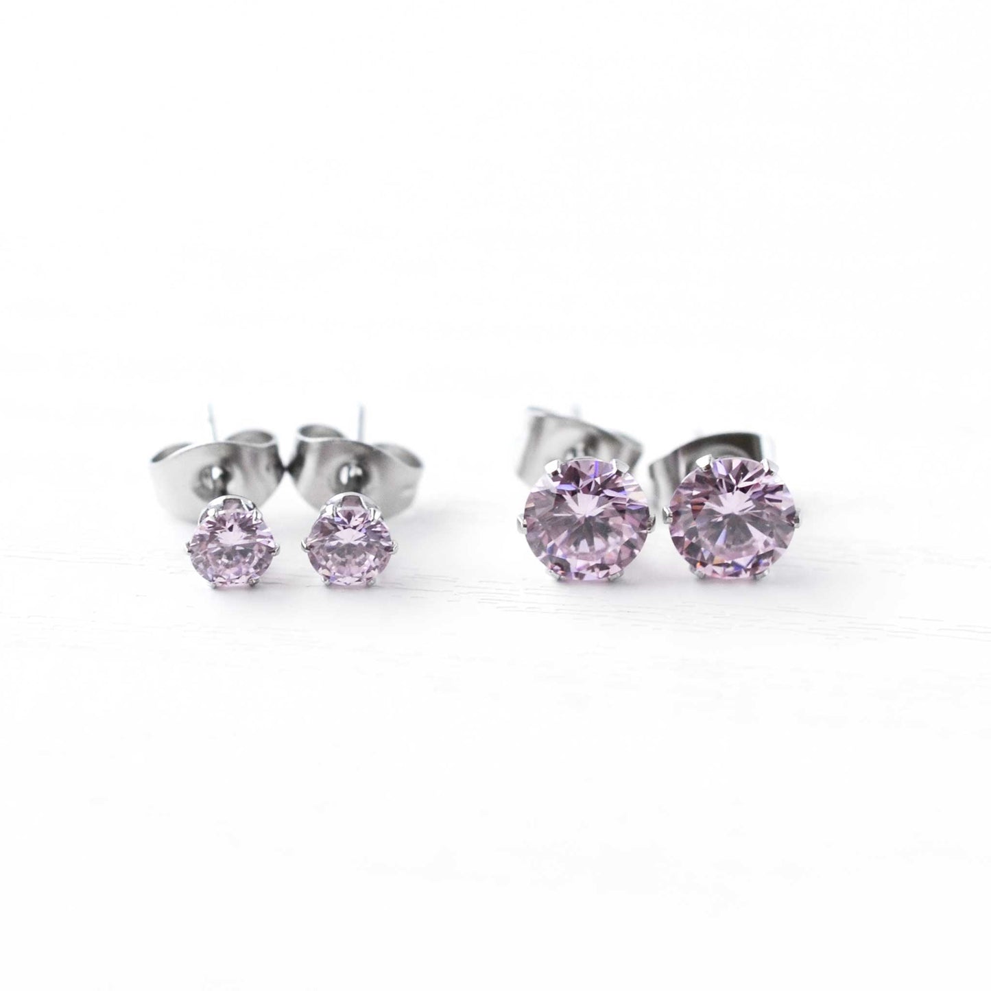 Pair of silver stud earrings with pink gemstones on a white background
