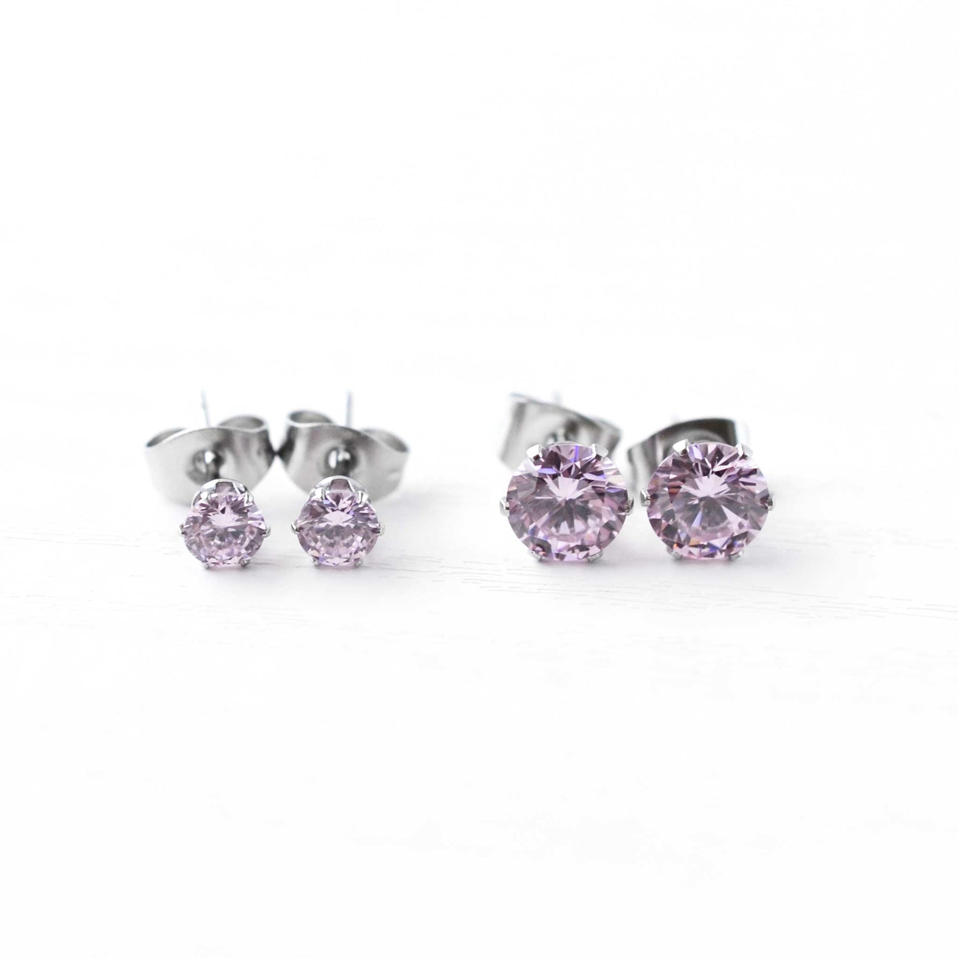 Pair of silver stud earrings with pink gemstones on a white background