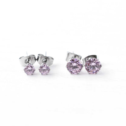 Pair of silver stud earrings with pink gemstones on a white background
