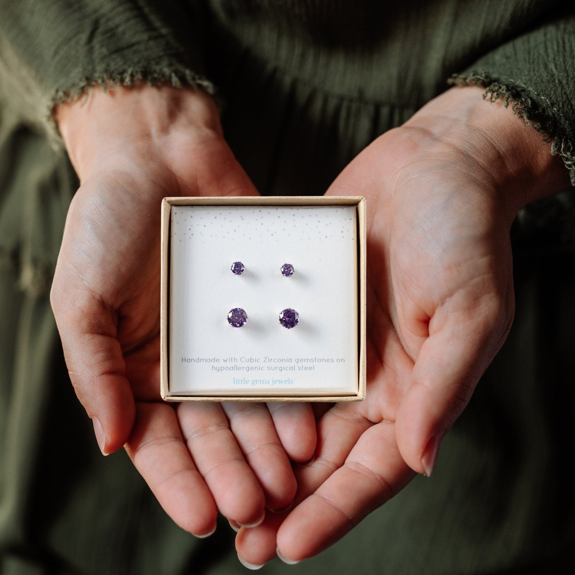 Hands holding a box with purple earrings