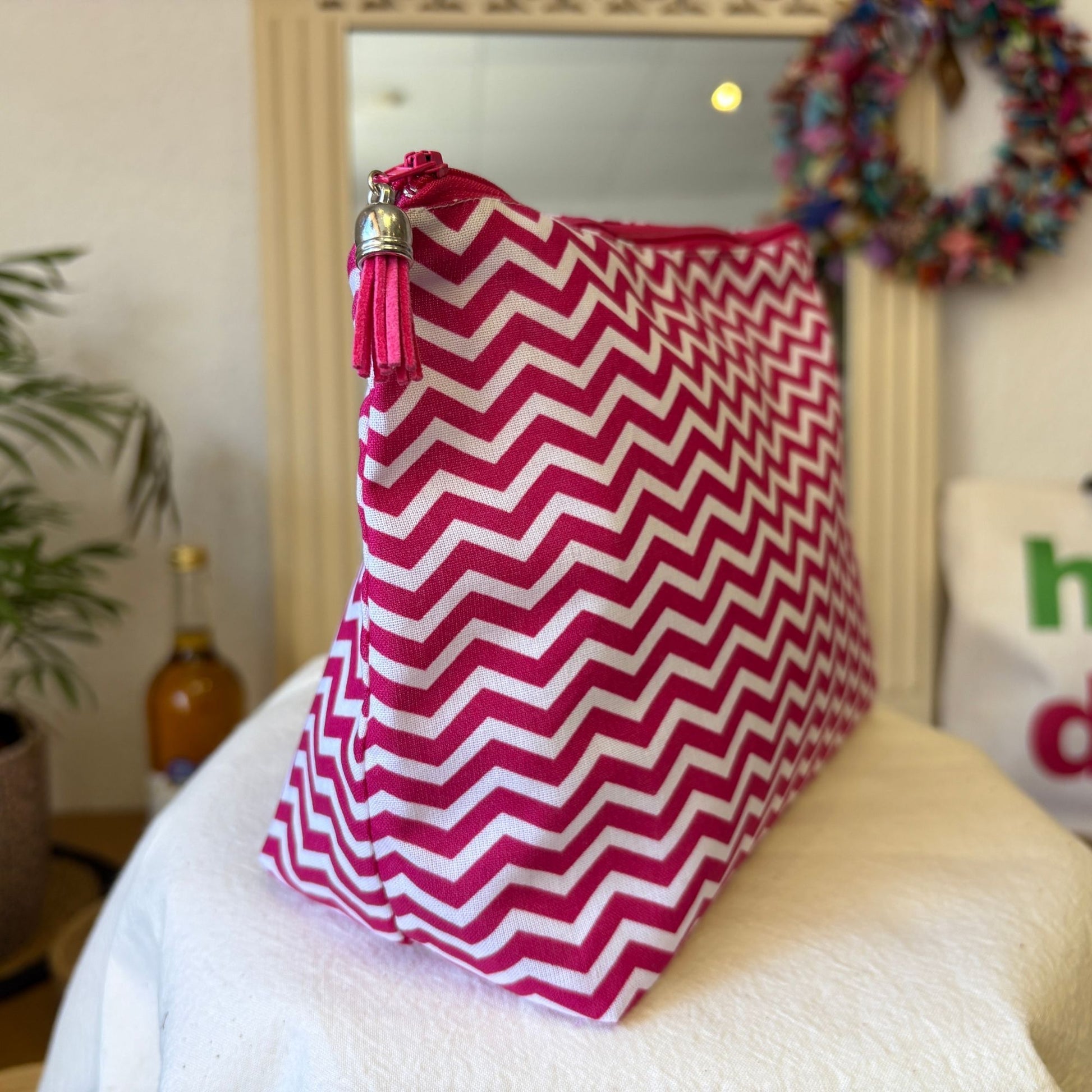 Pink and white zigzag-patterned bag with a tassel on a chair