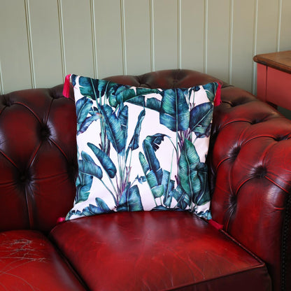 Rainforest velvet cushion with raspberry tassels on a deep red leather Chesterfield sofa